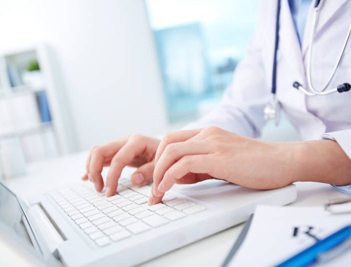 Close-up of hands of a nurse typing on laptop