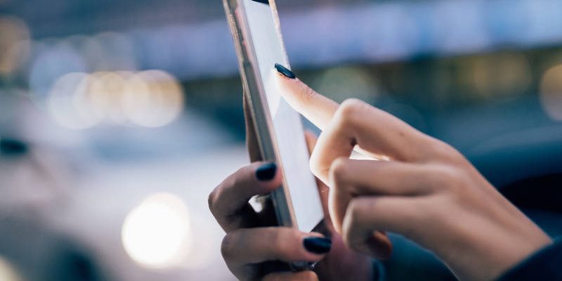 graphicstock-close-up-on-the-hand-of-young-woman-using-a-smartphone-tapping-the-screen-in-city-dusk-technology-communication-social-network-concept_S6oGvTY1b